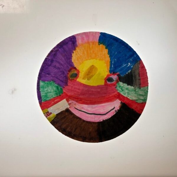 A brightly colored smiling face on a paper plate.
