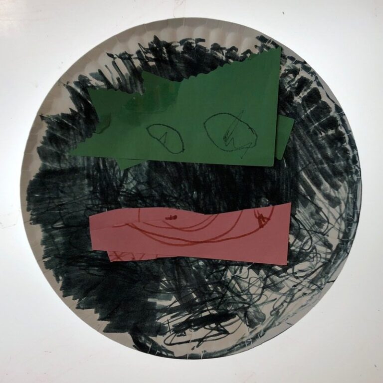 A dragons face made from a paper plate.